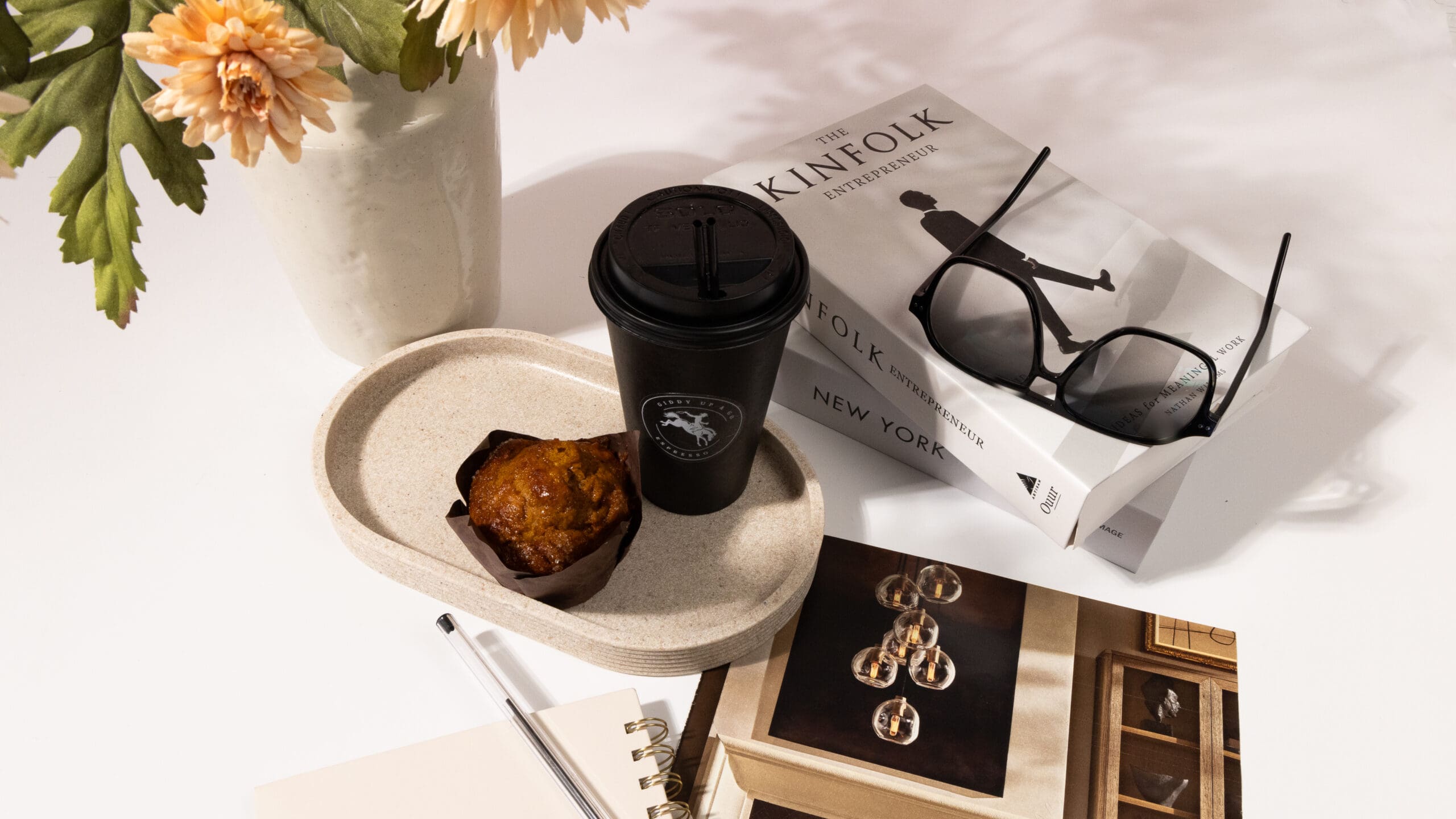 A curated studio planning table at Velvet Label featuring a marketing strategy book, an open notebook with handwritten notes, a pen, and a coffee cup, representing the intentional brand discovery and marketing ecosystem planning process.