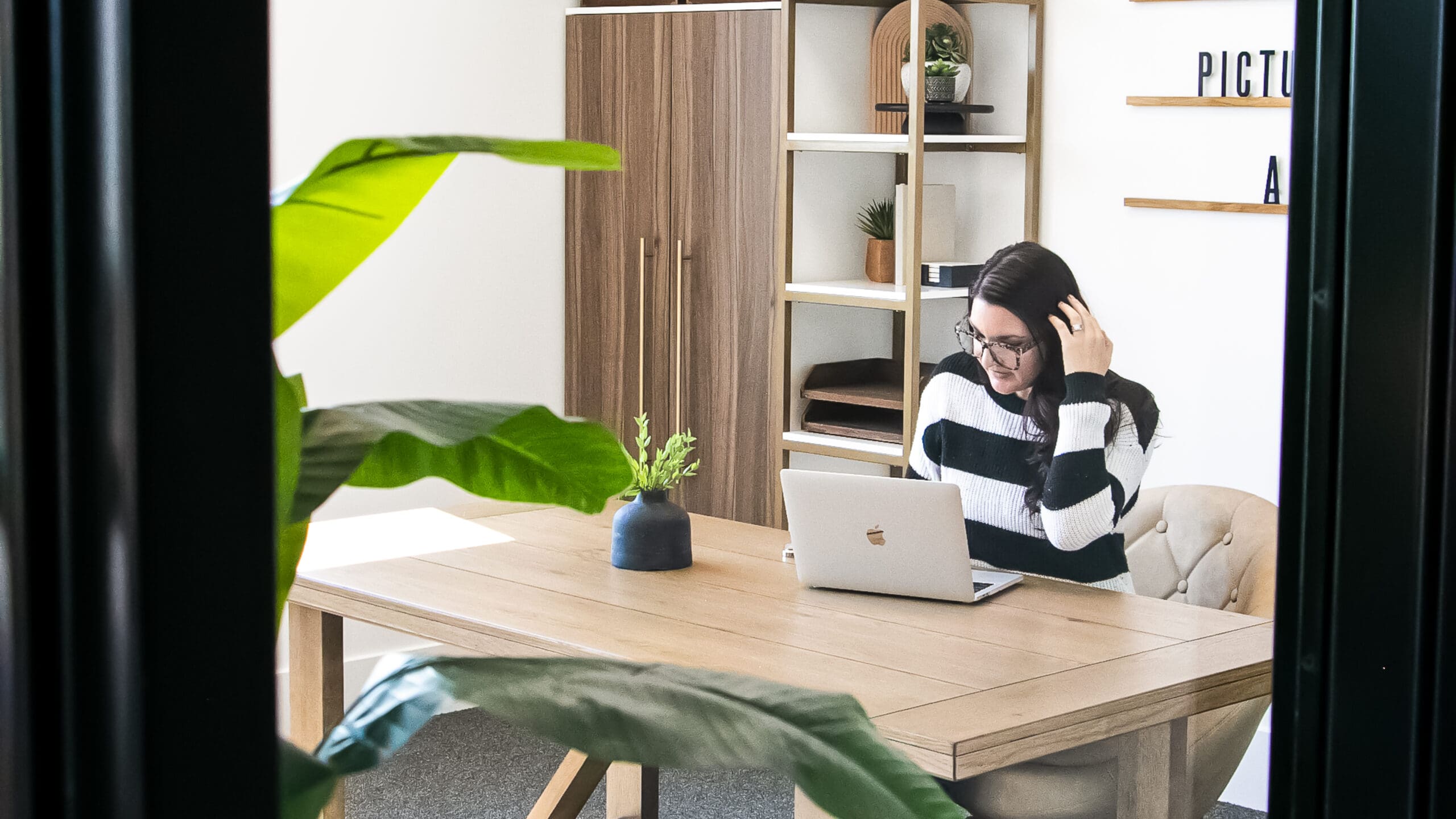 A focused female business owner standing at her desk, reviewing social media analytics on her smartphone to assess brand engagement and marketing ROI.