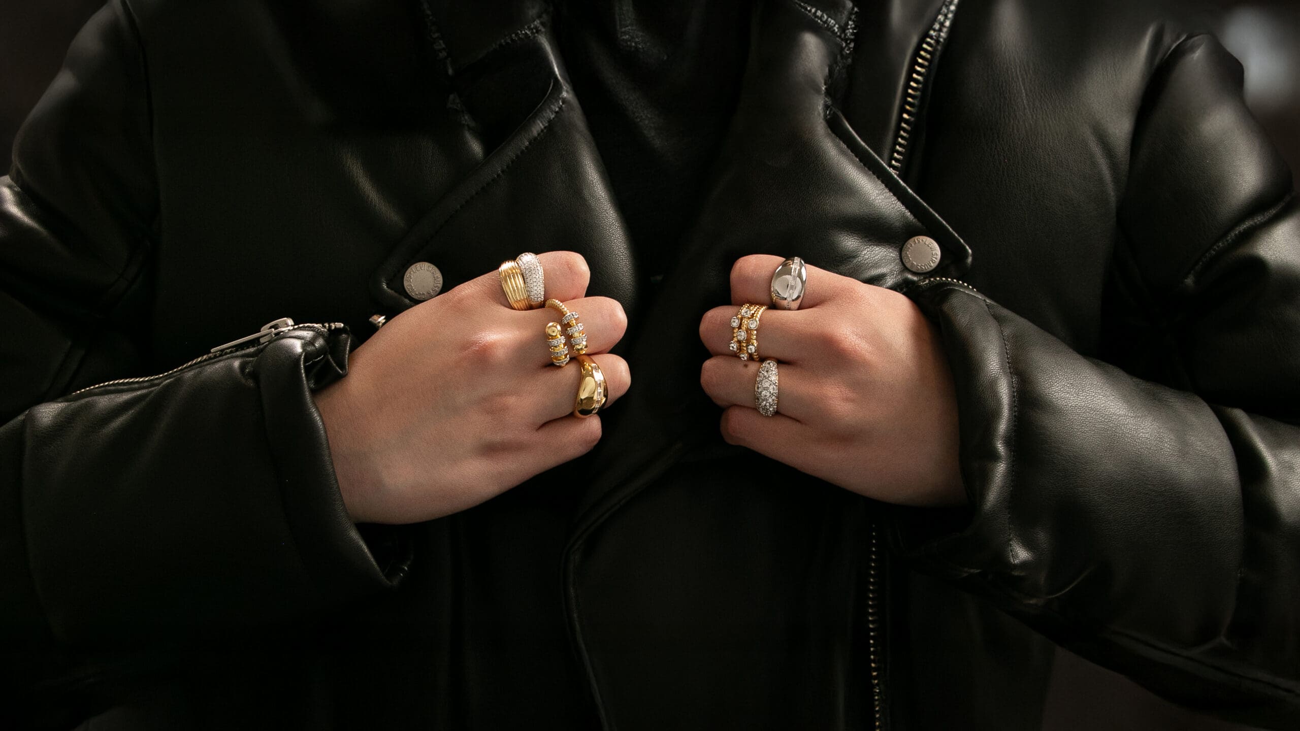 A close-up of a person in a black leather jacket wearing multiple gold and silver stylish rings, illustrating how narrative brand photography reflects the identity of a target audience.