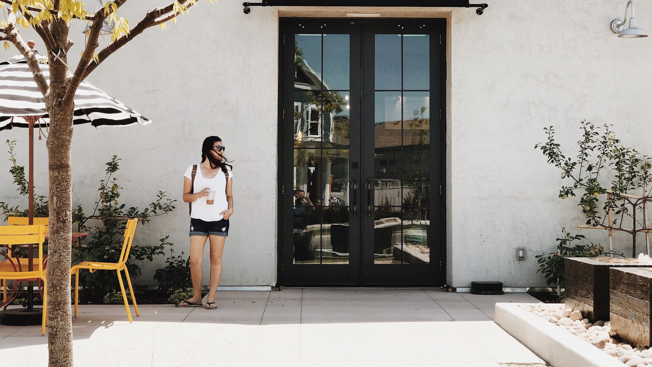 Velvet Label’s Director of Photography enjoying an iced coffee outside a local cafe, representing the mental clarity and work-life balance achieved through strategic business automations and a no-hustle philosophy.