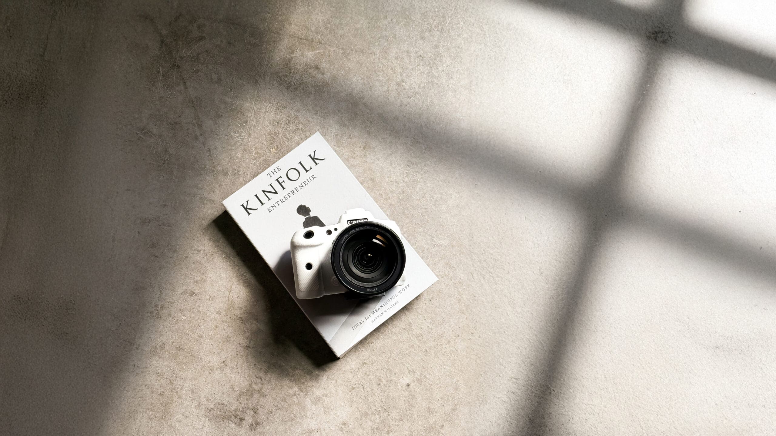 A professional camera resting on an entrepreneurship book on a concrete floor, illustrating Velvet Label's philosophy that everything is marketing.